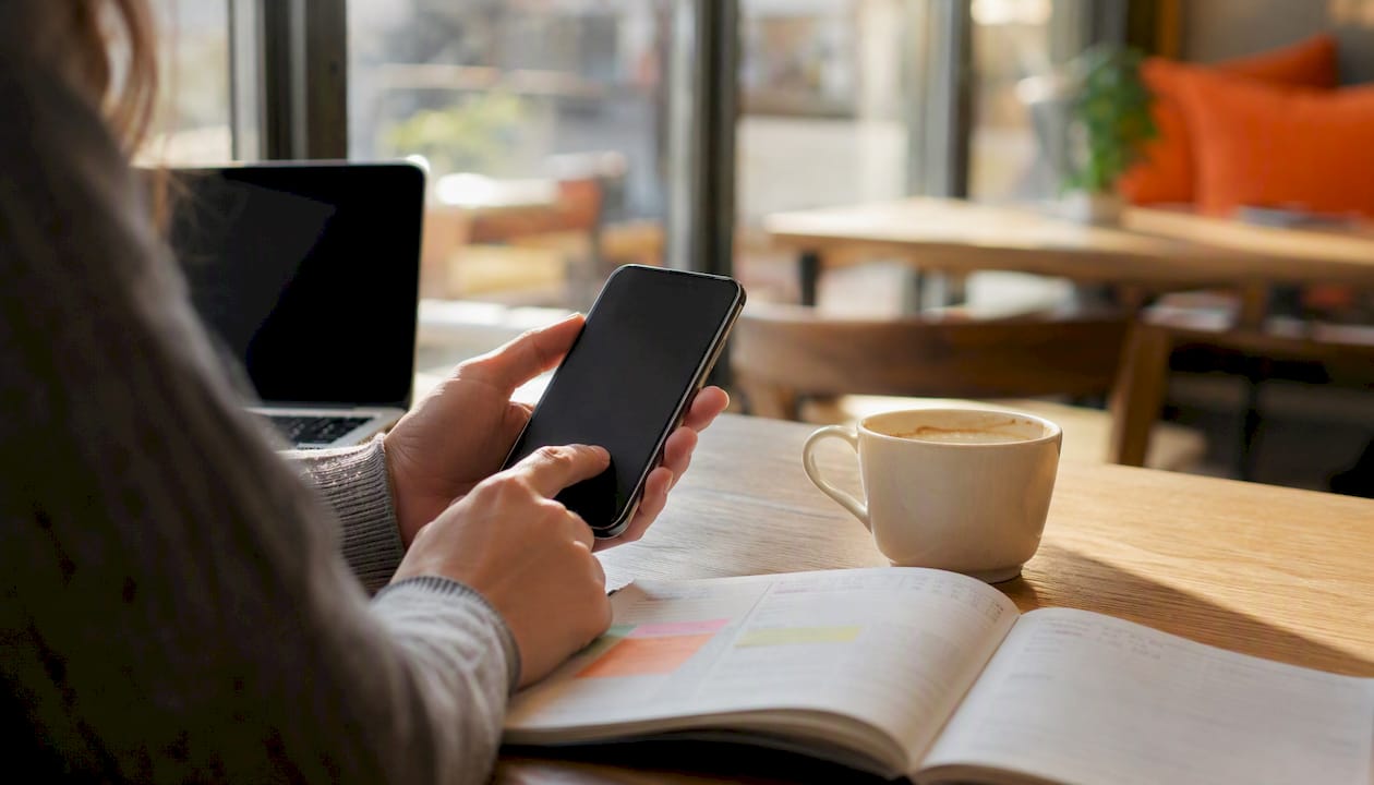 Mani che avviano un timer su una scrivania con caffè